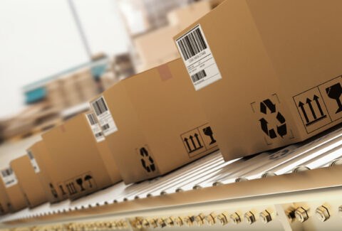 Packed,Courier,On,Production,Line,Against,Cardboard,Boxes,In,Warehouse